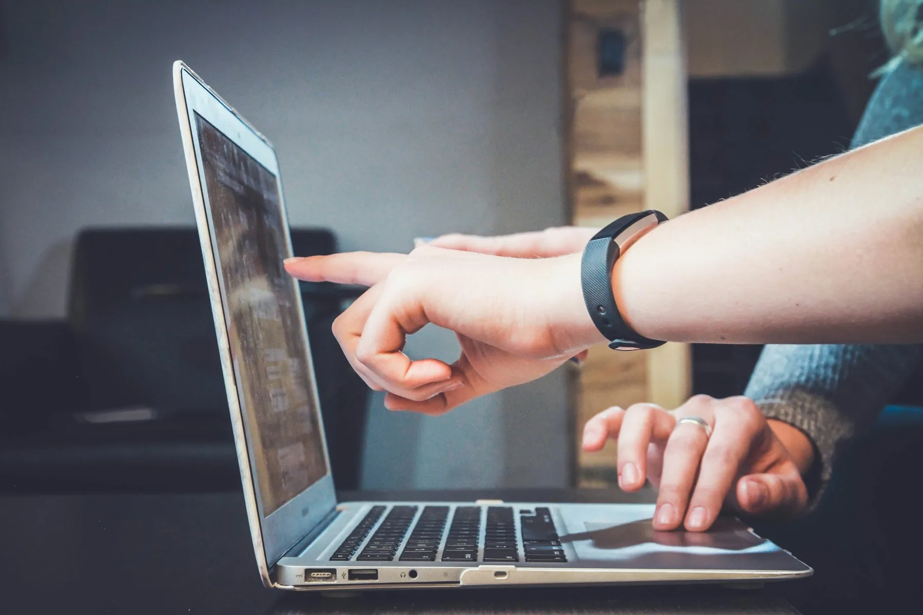 Two people working together and pointing at a laptop screen