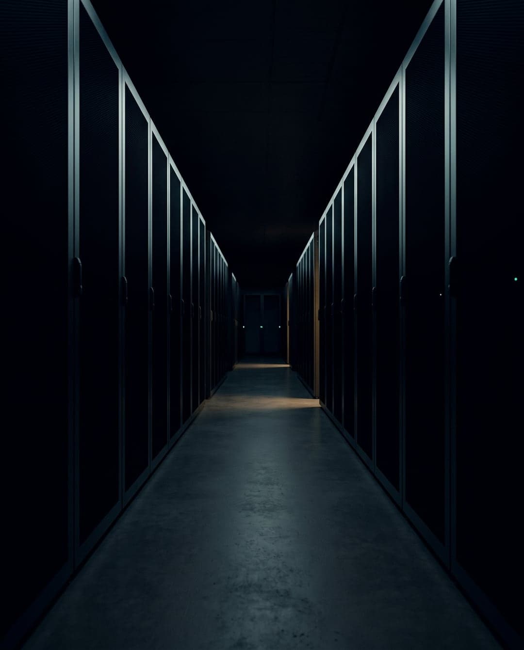 A dark server room aisle lit only along its edges