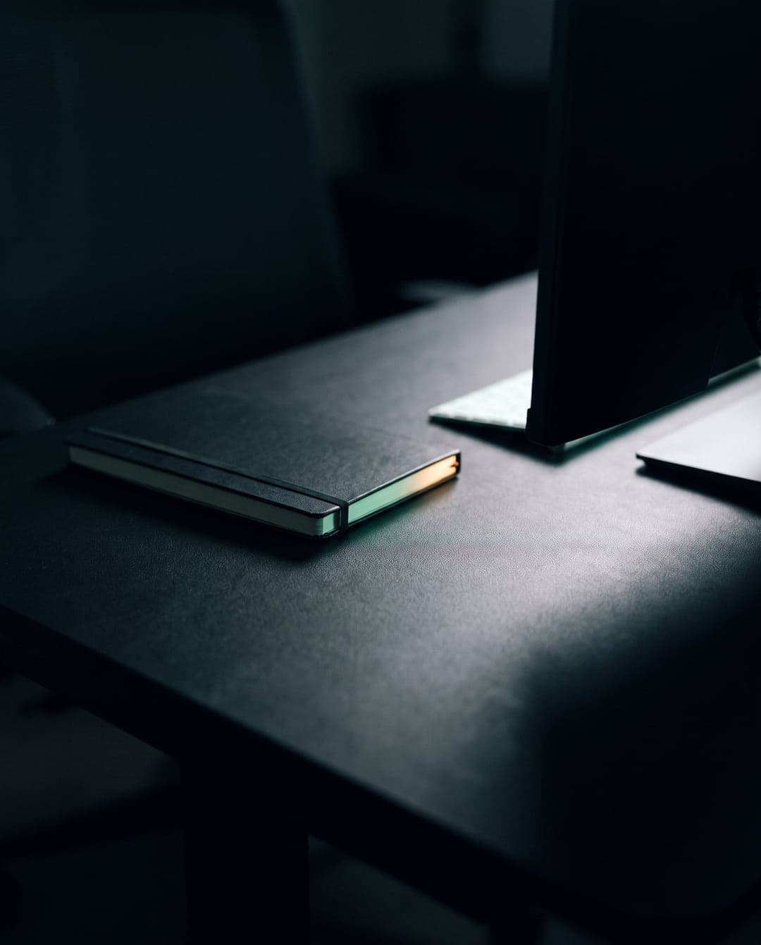 A dark desk at night lit by the edge of a monitor